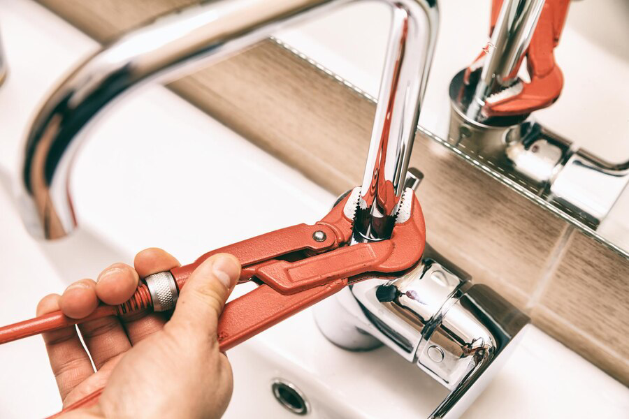 person tightening tap with alligator wrench