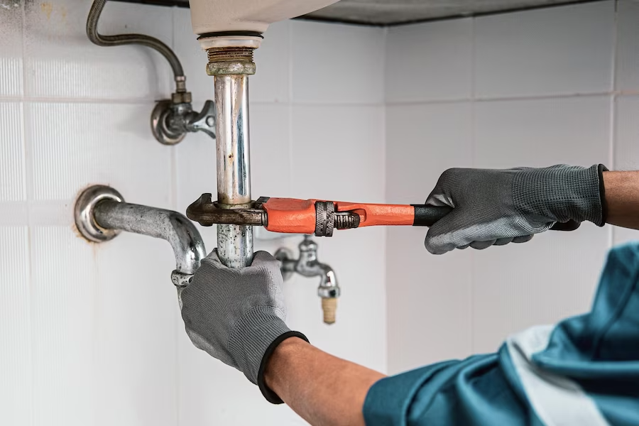 plumber using wrench repair water pipe sink